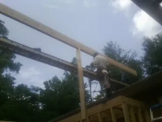 Carpenter setting a ridge beam over a new addition frame — Ice Dam Removal by Roofing Brothers in Oakboro