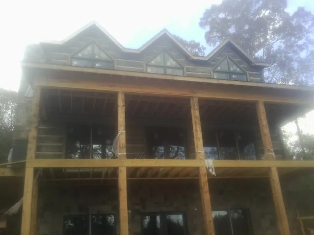 Dormers and porch framing on a large log home under construction — Roof Coating work by our crew in Oakboro