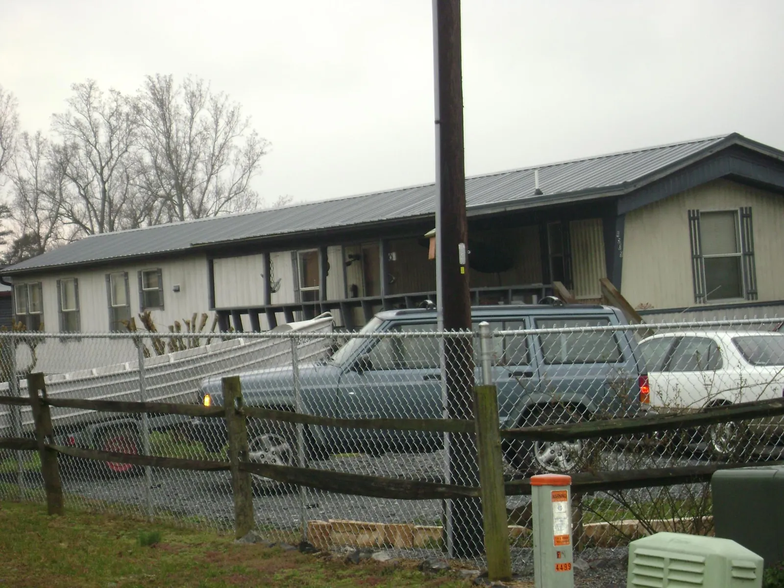 Dark metal roof on a long single story building behind a chain link fence in Oakboro
