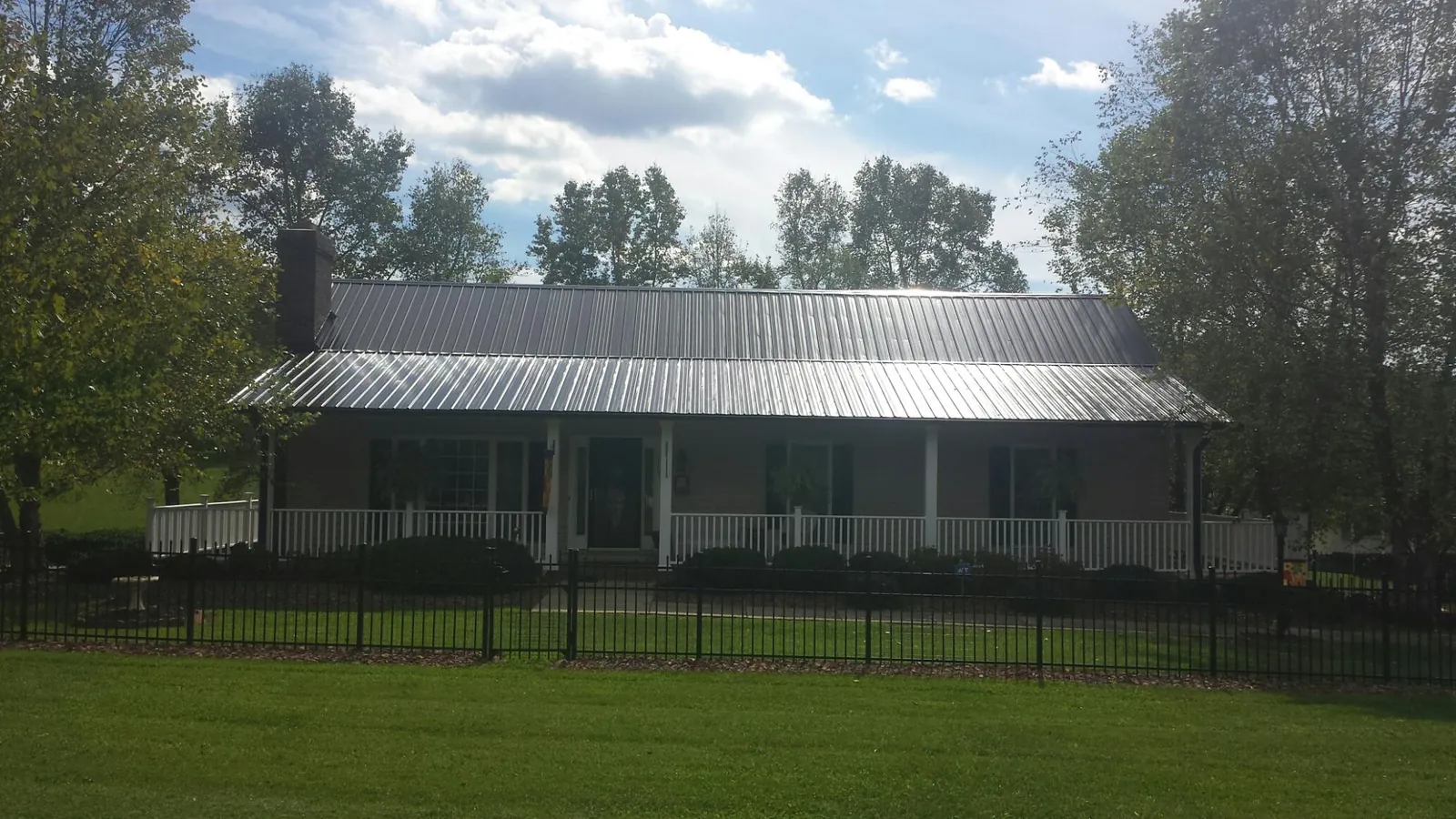 Gray metal roof on a brick ranch with a full width front porch — Gutter Guard Installation work by our crew in Oakboro