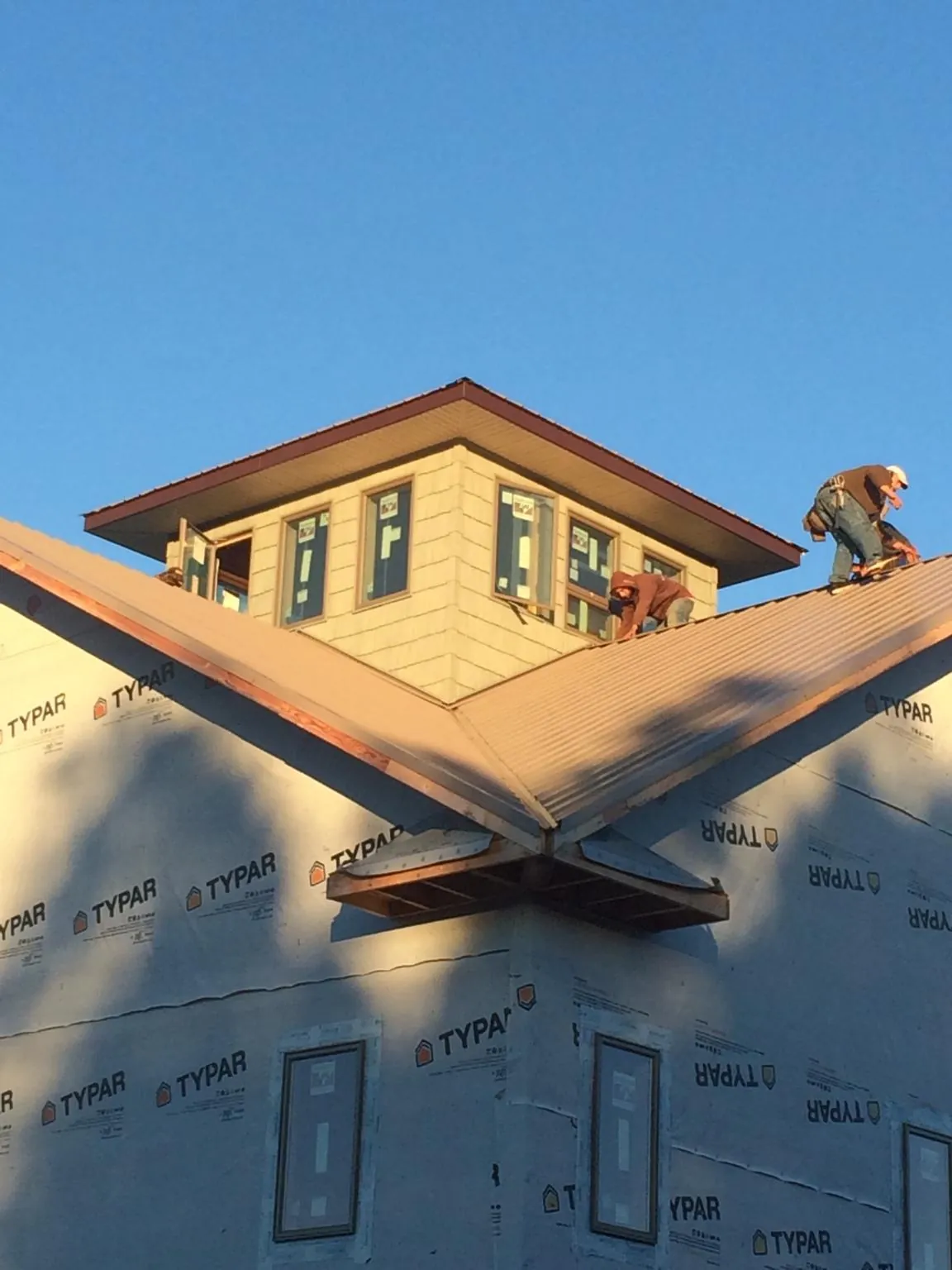 Roofers working around a rooftop cupola on a new metal roof at sunset — Roof Waterproofing in Oakboro by Roofing Brothers